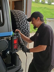 detailing tech with a buffer working on the back of a jeep