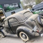 black, classic Plymouth car in front of detail shop. it is very dusty and dirty